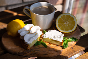 Lemon tartlets with basil on wooden desk and Cup of coffee on wooden table.