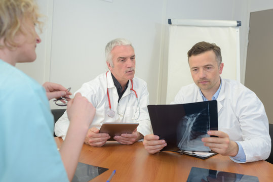three busy concerned doctors checking patients xray