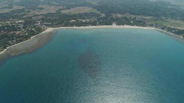 Beautiful tropical beach Cabugao with white sand and palm trees in the Philippines, Luzon. Aerial view of coast with beach and turquoise water.