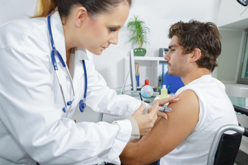 physiotherapist injecting male patient in clinic