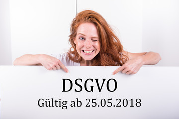 schöne rothaarige Frau hält ein weisses Brett mit der Aufschrift DSGVO