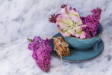 Spring Table Setting with Vintage Blue Cutlery and Lilac Flowers on a Marble Background.Floral Table Decor