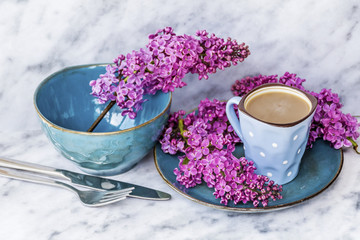 Spring Table Setting with Vintage Blue Cutlery and Lilac Flowers on a Marble Background.Floral Table Decor