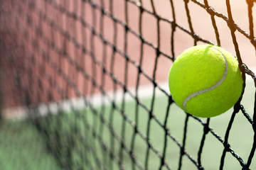Tennis ball hitting to the net on court background