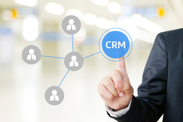 Businessman hand touch CRM, Customer Relationship Management, icon over blur background, success in business concept