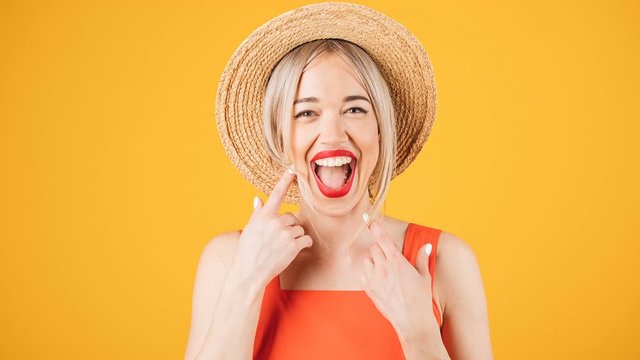 Adorable smiling blonde cute woman in straw hat on yellow background. Positive happy emotions. Stop motion video footage
