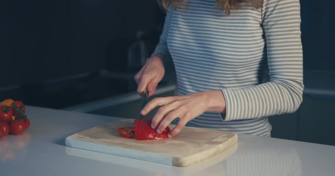 Young woman chopping red pepper