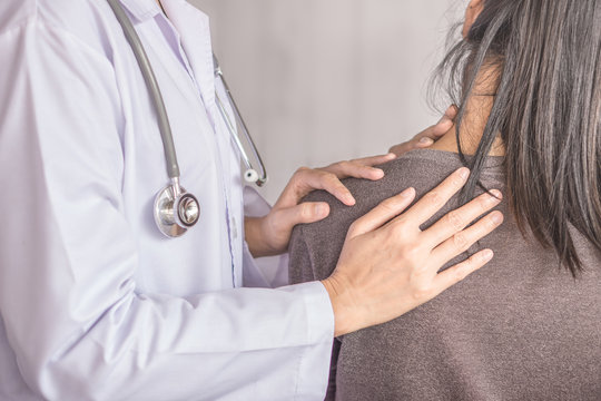 female doctor examining a patient suffering from neck and shoulder pain 