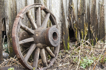 Old classic wooden wheel on old wooden fence background. Copy space