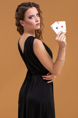 Beautiful brown-haired woman holding two aces as a sign for poker game, gambling and casino