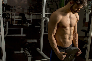 Fototapeta na wymiar Half-naked man with weight in the gym