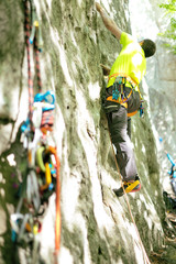 Detail of young man who preparing on a climb and standing a next to rock wall. Equipment for climbing on a man with copy space for a text. 