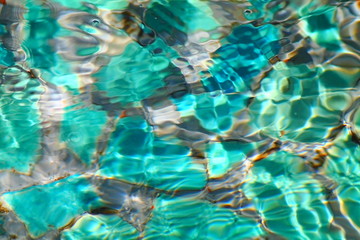 Clear swirling swimming pool water.  Light spots and waves over bottom ceramic tiles.