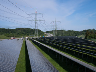 Photovoltaikanlage mit Strommasten und Autobahn