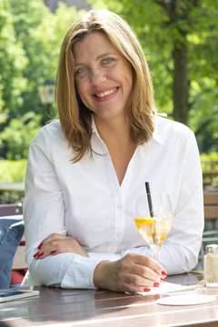 Frau im Biergarten trinkt einen Cocktail