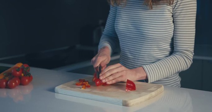 Young woman cutting red pepper
