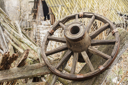 Old wooden wheel on background of ruins of old farm. Copy space