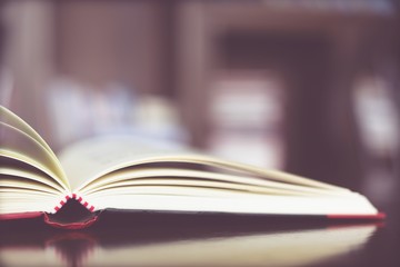 Open book page are placed on a wooden table and bookshelf in a library. education concept. with filter Tones retro vintage warm effect.