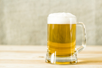A mug of fresh beer with foam.