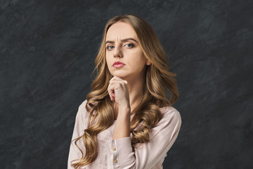 Fototapeta premium Pensive woman touching her chin, copy space