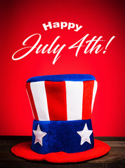 A felt colorful Uncle Sam hat on red background with Happy July 4th greeting