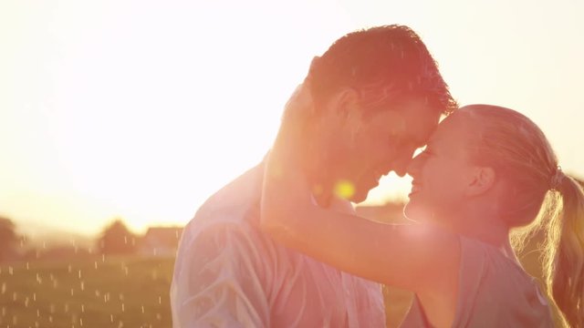 SLOW MOTION, CLOSE UP, LENS FLARE: Young Caucasian woman and man madly in love hold each other tight while dancing at sunset. Lovely couple shares unforgettable moments as the dance in golden nature.