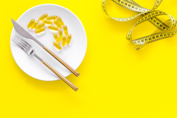 Dietary supplement for well-being. Fish oil or omega-3 capsules on plate near measuring tape on...