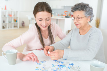 granddaughter solving puzzle with the help of her grandmother