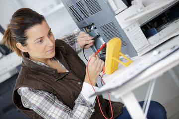 woman mesuring the voltage of a machine