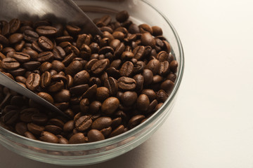 Closeup of bowl with roasted coffee beans on white background