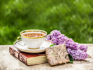 Cup of fragrant tea, fresh lilac and gift. Romantic concept. Seasonal concept. Tea in the garden. Copy space - Powered by Adobe