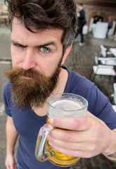 Guy having rest with cold draught beer. Man with beard and mustache holds glass with beer while...