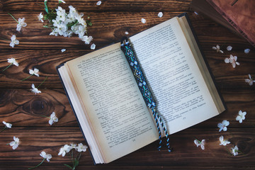 Fototapeta na wymiar open book with bookmark on wooden background with white flowers