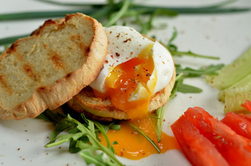 Poached egg on toast with arugula and tomatoes