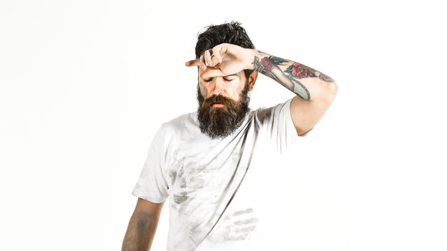 Man with beard in dirty dusty shirt looks exhausted.