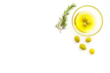 Make olive oil concept. Green olives in bowl with olive oil on white background top view copy space