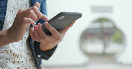 Woman use of mobile phone in Chinese garden