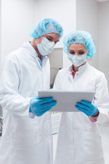 Two scientists working together in lab looking at data on a tablet computer