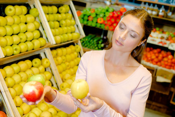 Young woman contemplating apples