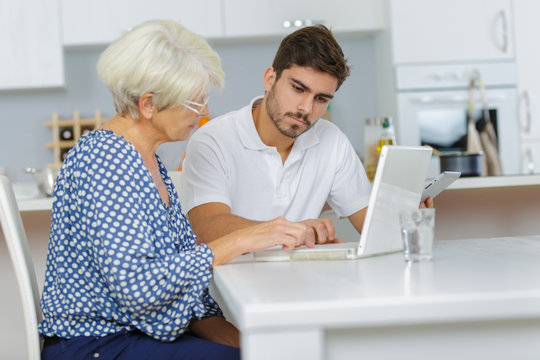 man teaches an elderly woman how to work using laptop