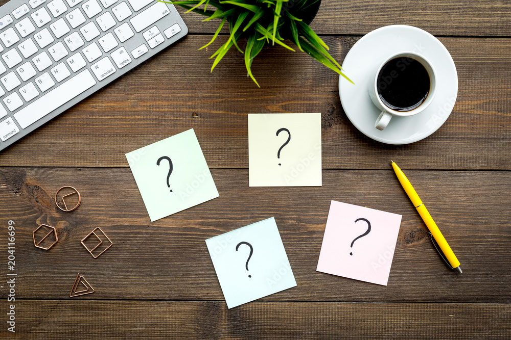 Poster question mark on sticky notes on office desk on dark wooden background top view. faq concept. workin