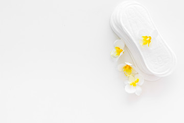 Women's hygiene products. Critical days concept. Sanitary pads near small flowers on white background top view copy space