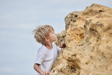Little cute boy on sea coast playing with rocks