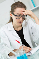 portrait of young female scientist writing research results