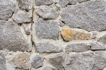 Fragment of gray stone wall with cement solution. Front view