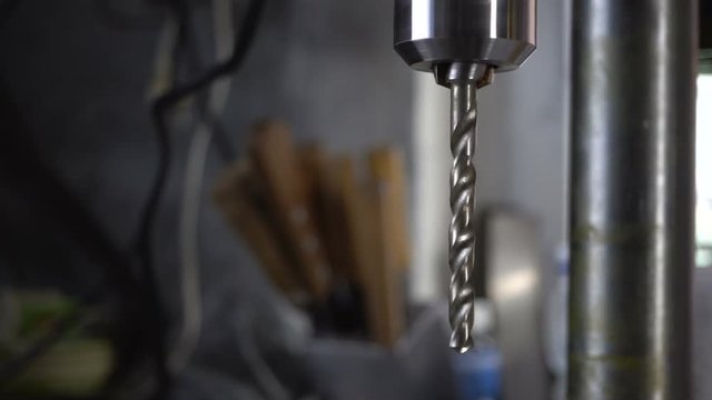 The movement of the pulley and the drill of the drilling machine on a grey background.