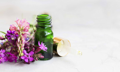 Essential oil in a bottle with flowers and glass dropper, aromatherapy