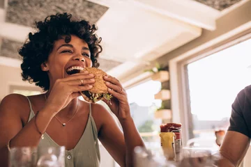 Foto op Aluminium Vrouw geniet van het eten van hamburger in restaurant © Jacob Lund