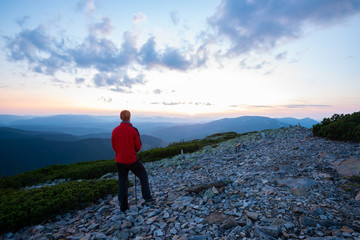 Obraz premium Adventurer admiring the panorama of the mountains during sunset