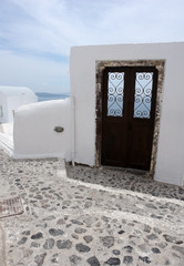 A brown door with a decorative lattice in a white wall on the island of Santorini.